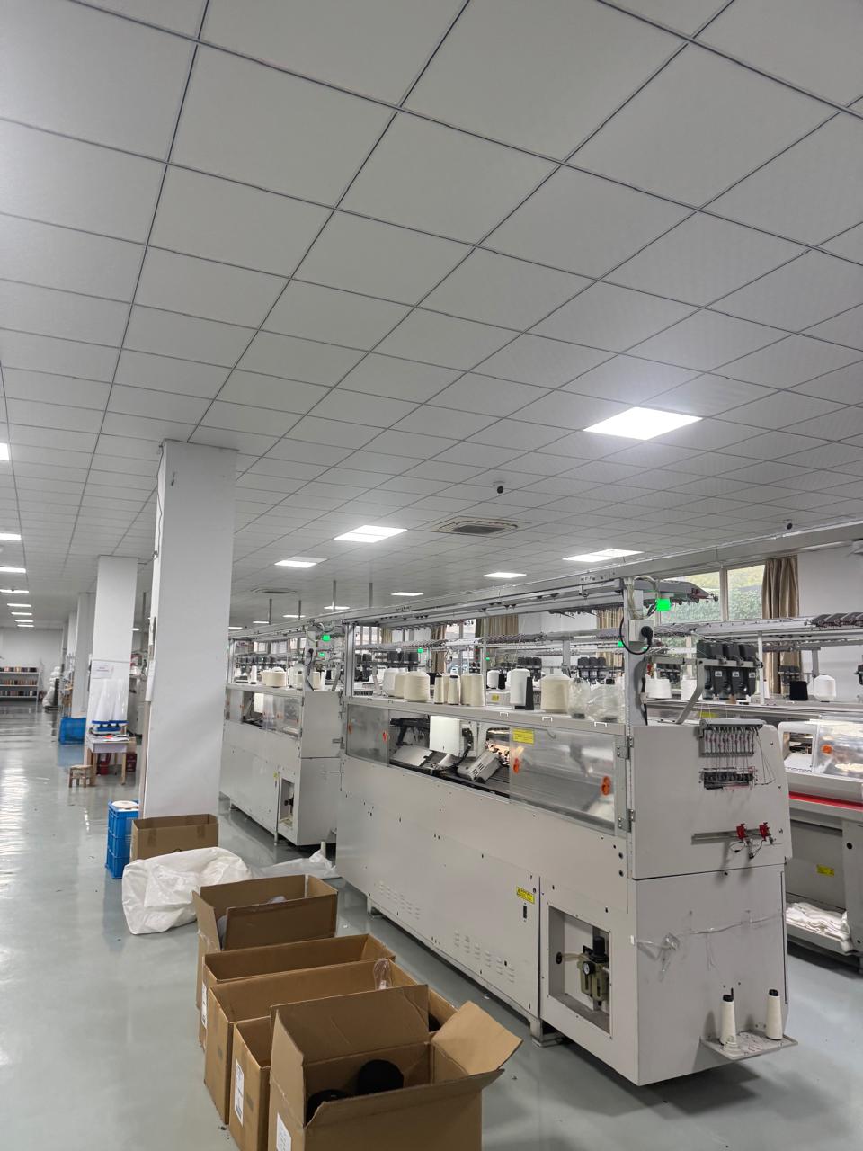Row of circular knitting machines producing fabric
