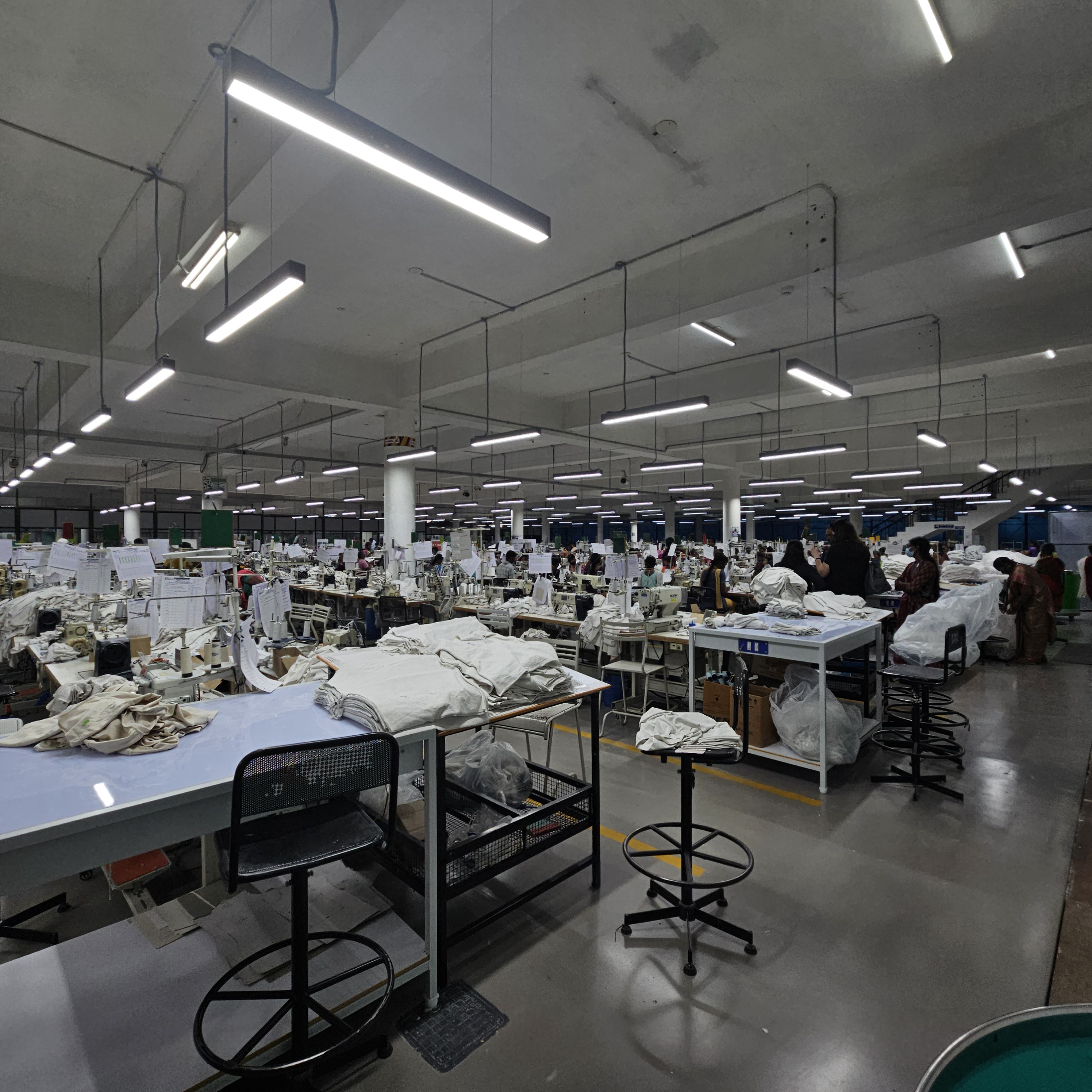 Overhead view of sewing floor workstations with garments